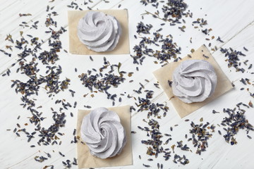 Freshly made lavender marshmallows on white painted boards. The surface is sprinkled with lavender flowers. View from above.