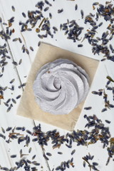 Freshly made lavender marshmallows on white painted boards. The surface is sprinkled with lavender flowers. View from above.