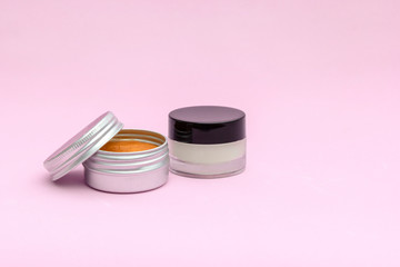 Blank silver and glass cream jar on light pink background. Cosmetic skincare products, modern concept of organic beauty trend.