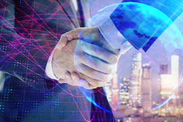 Double exposure of world map on cityscape background with two businessmen handshake. Concept of international business