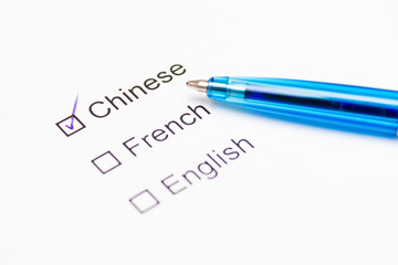Chinese, French, English - checkmark with pen on paper.