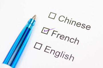Chinese, French, English - checkmark with pen on paper.
