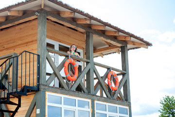 Naklejka premium Lifeguard tower for rescue baywatch on beach. Wooden house on sea shore on cloudy sky background. Summer vacation and resort. Public guarding and safety concept