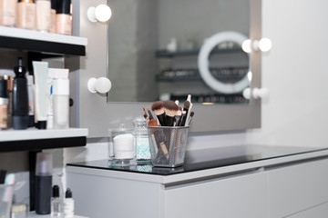 Professional makeup brushes set closeup near salon mirror. Brush any size for professional make-up artist on blur background