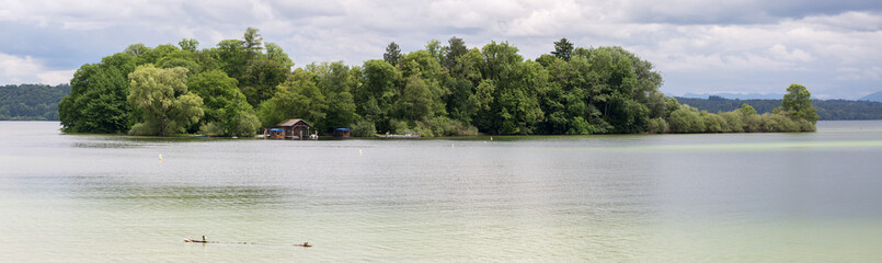 FELDAFING, BAVARIA / GERMANY - June 16, 2019: Panorama view of the Roseninsel (rose island) at Lake Starnberg. Famous rose garden. The pile dwellings around the island are an Unesco World Heritage.