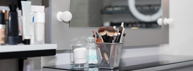 Professional makeup brushes set closeup near salon mirror. Brush any size for professional make-up artist on blur background