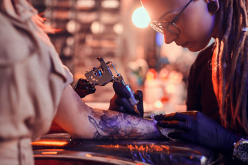 Process of creating new tattoo for young woman by expirienced tattoo artist at studio.