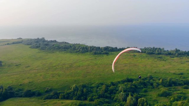 A person on a paraplane is doing tricks while flying. Parachute, paragliding comcept.