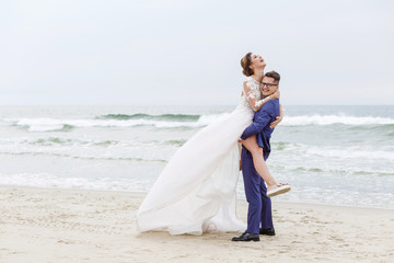 Fototapeta na wymiar The groom whirls his bride on the beach