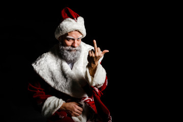 Portrait of a bad brutal mature Santa Claus showing middle finger signs, isolated on black...
