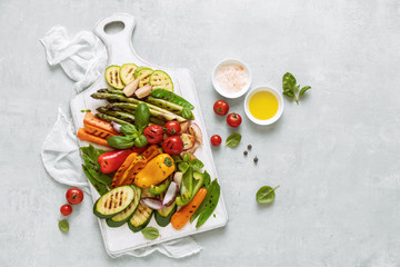 Grilled assorted vegetables on a kitchen board, top down view, space for a text