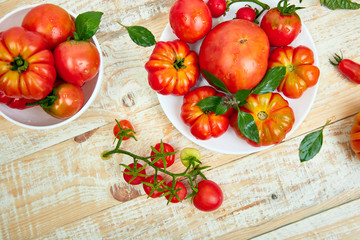 Mix of tomatoes background. Beautiful juicy organic red tomatoes on white wooden table background. Clean eating concept. Copy space, flat lay..