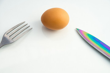 steel dining fork in the egg shell and butter knife on a white background closeup
