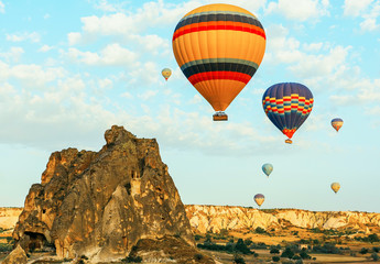 Obraz premium Colorful air balloons fly up into the sky at sunrise among a beautiful rocky landscape. Cappadocia Turkey.