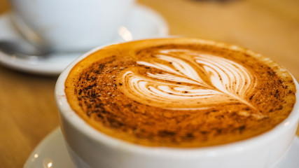 Latte art drawing on a milk foam, cappuccino coffee in the cafe  