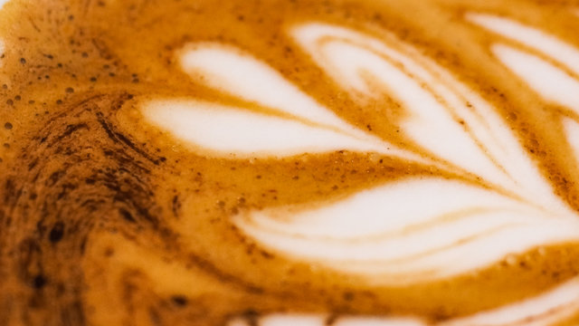 Latte art drawing on a milk foam, cappuccino coffee in the cafe  