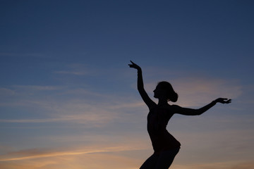 Fototapeta na wymiar dancer in the dance does the splits in the air against the sunset.