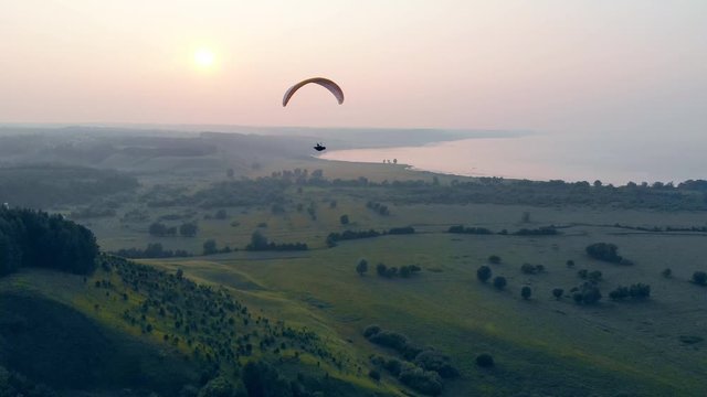 Green foggy scenery with a parafoil drifting along it. Parachute, paragliding comcept.