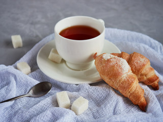 cup of tea, croissants, sugar cubes on on a white napkin