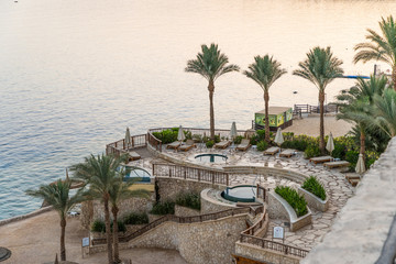 Fototapeta premium Sharm El Sheikh, Egypt - May 2019: Beautiful sunny beach and parasols on the coast of the Red Sea in the city of Sharm El Sheikh, Egypt. Tourist recreation area on the Sinai Peninsula
