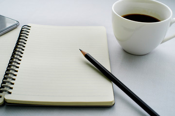 Coffee in white cup with Journal book and pencil