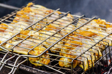 Chicken wings are laid on grill. Selective focus. Cooking barbecue chicken wings on coals on grill. Lattice with chicken wings over glowing coals. Blurred background.