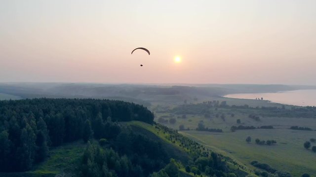 Sailwing is drifting high in the sunlit sky. Paraglider in the sky.