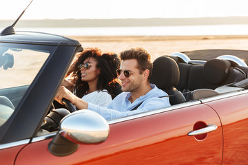 Beautiful young multiethnic couple riding in a convertible