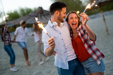 Happy group of friends lighting sparklers and enjoying freedom