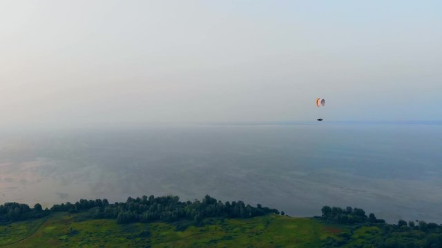 Vast waterscape and a paraplane gliding above it. Parachute, paragliding comcept.