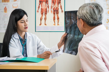 Fototapeta premium Expert doctor examining and explaining x-ray film to elderly patient in medical office.