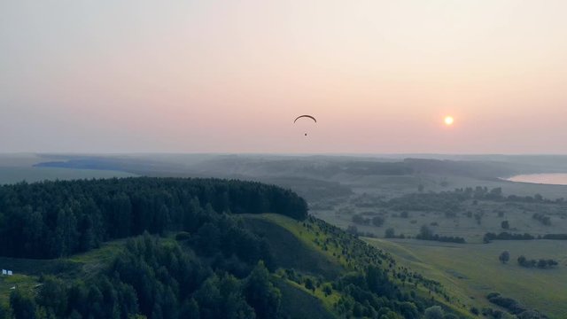 Paraglider in the sky. Green foggy scenery with a sailwing flying high in the sky