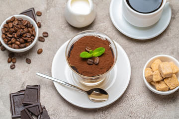 Classic tiramisu dessert in a glass, coffee, chocolate, cream and sugar on concrete background