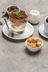 Classic tiramisu dessert in a glass, coffee, chocolate, cream and sugar on concrete background