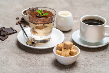 Classic tiramisu dessert in a glass, coffee, chocolate, cream and sugar on concrete background