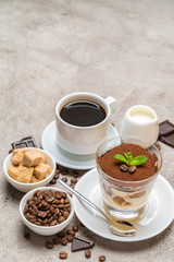 Classic tiramisu dessert in a glass, coffee, chocolate, cream and sugar on concrete background