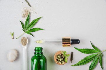 Glass green bottle and pipette with CBD oil and cannabis leaf on background. Minimal concept. Flat...