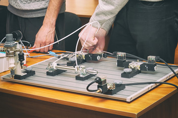 Engineers connect wires control panel with a small test bench for experiments