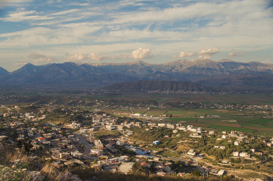 Panorama of the city, valley and cultivated fields in beams of the evening sun. View from the ruined Lekuresi Castle. Nature and travel. Albania, Vlora County, near Saranda