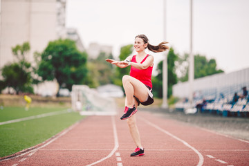 Obraz premium Female athlete preparing legs for cardio workout. Fitness runner doing warm-up routine. woman runner warm up outdoor. athlete stretching and warming up on a running track in a stadium