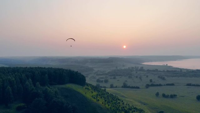 Ram-air parachute is drifting in the sky while the sun is setting