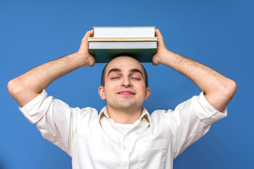 Happy guy white shirt with books on his head, smiling, close up