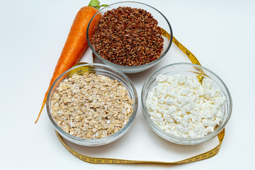 raw chicken breast, cereals, brown rice, measuring tape, farm cottage cheese carrot close up on white background protein healthy diet fat free concept eco product sports nutrition
