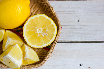 Lemon slices on a white background with a green sprig in a wicker bowl