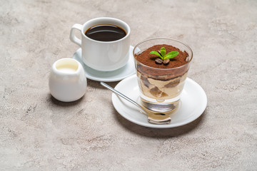 Classic tiramisu dessert in a glass, cup of espresso coffeeand cream on concrete background