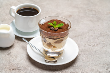 Classic tiramisu dessert in a glass, cup of espresso coffeeand cream on concrete background