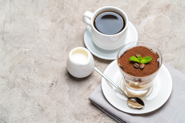Classic tiramisu dessert in a glass, cup of espresso coffeeand cream on concrete background