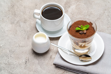Classic tiramisu dessert in a glass, cup of espresso coffeeand cream on concrete background