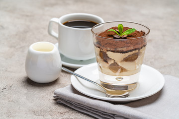 Classic tiramisu dessert in a glass, cup of espresso coffeeand cream on concrete background