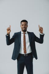 happy african american man pointing with fingers isolated on grey